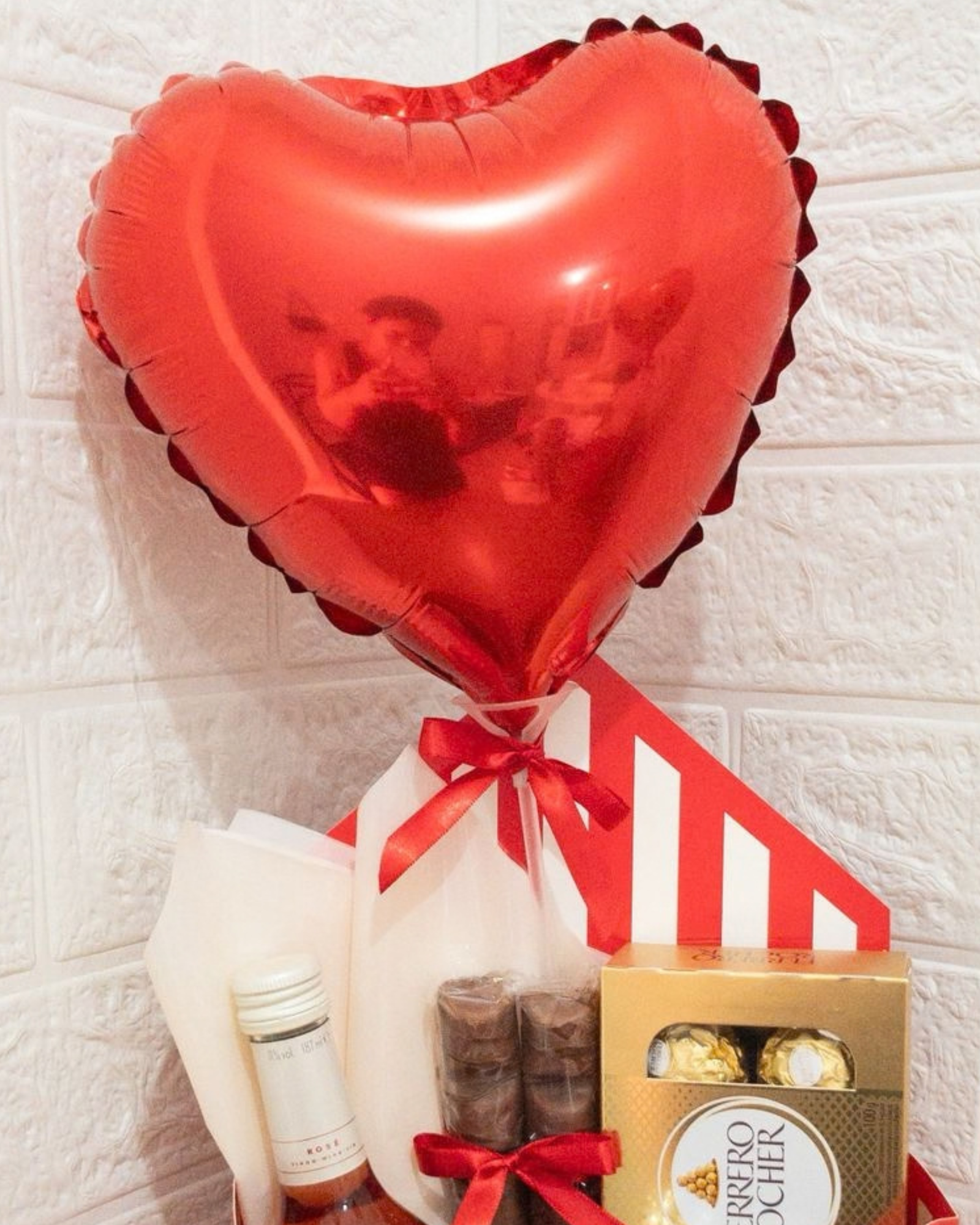 Cesta de Vinho e Chocolate 2 Balão metalizado de coração vermelho flutuando sobre a cesta envelope com vinho rosé e chocolates