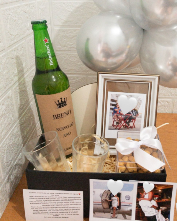 Cesta Box Happy Hour a Dois 5 Variação da Box Happy Hour a Dois com cerveja Heineken personalizada, copos Lagoinha, amendoins com laço branco, moldura, polaroids e balões prateados ao fundo