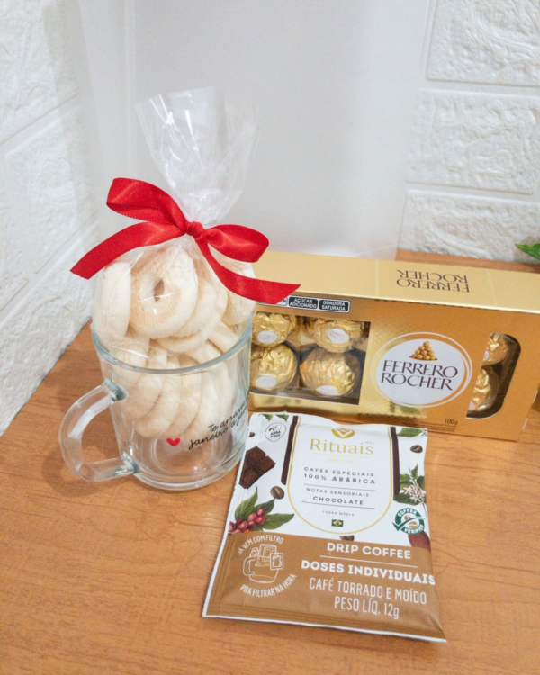 Cesta Bag Café com Amor 2 Detalhe dos itens da Bag Café com Amor com xícara de vidro cheia de biscoitos amanteigados, caixa de bombons Ferrero Rocher e um sachê de café Drip Coffee.